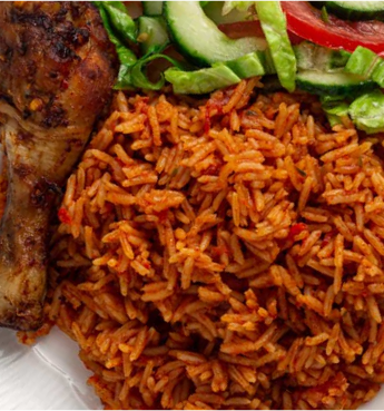 A plate of Jollof rice and chiken and some vegetables.